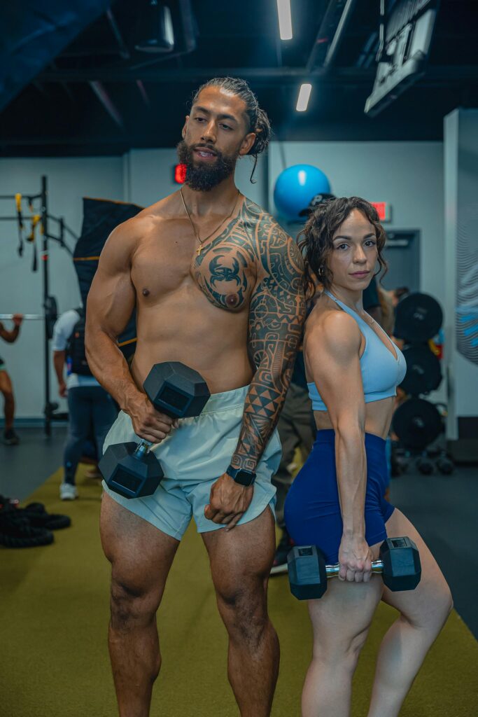 pexels photo 12931805 12931805 A muscular couple lifting dumbbells in a modern gym setting, showcasing fitness and strength.