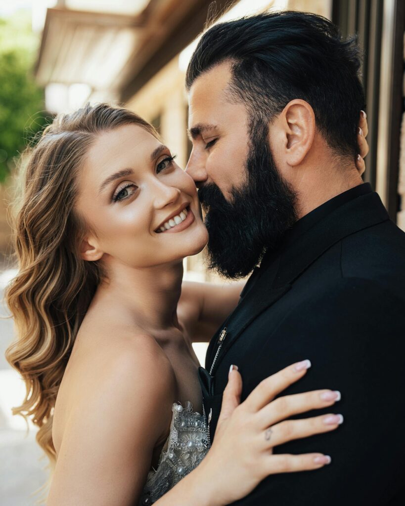 A loving couple shares an intimate moment outdoors, basking in warm sunlight, expressing romance and happiness.