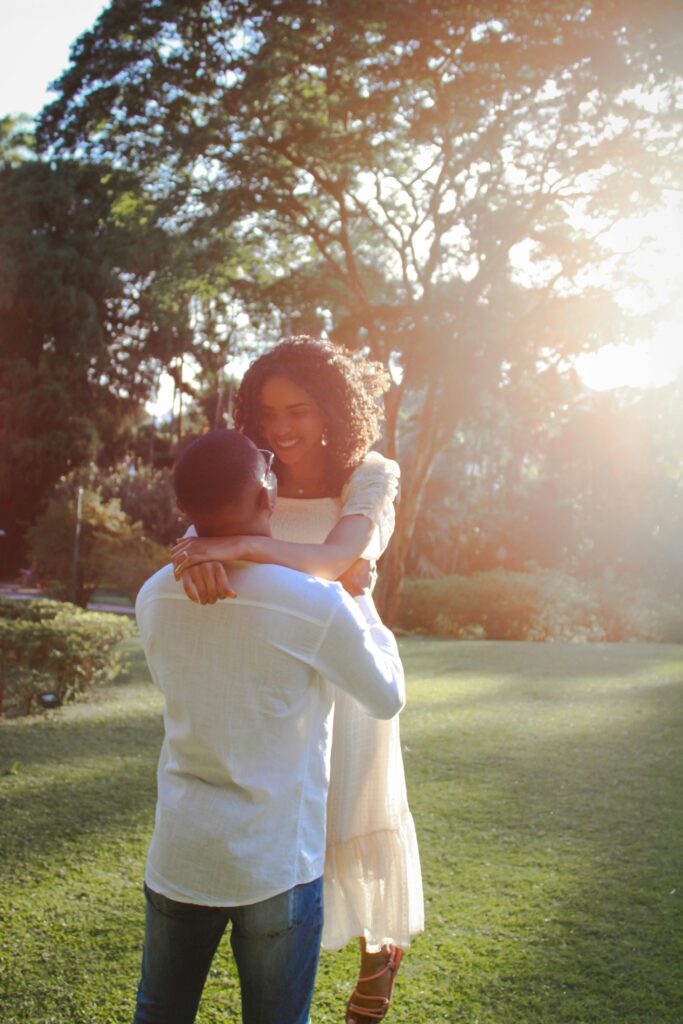 A couple shares a romantic embrace in a sunlit garden setting, evoking warmth and love.