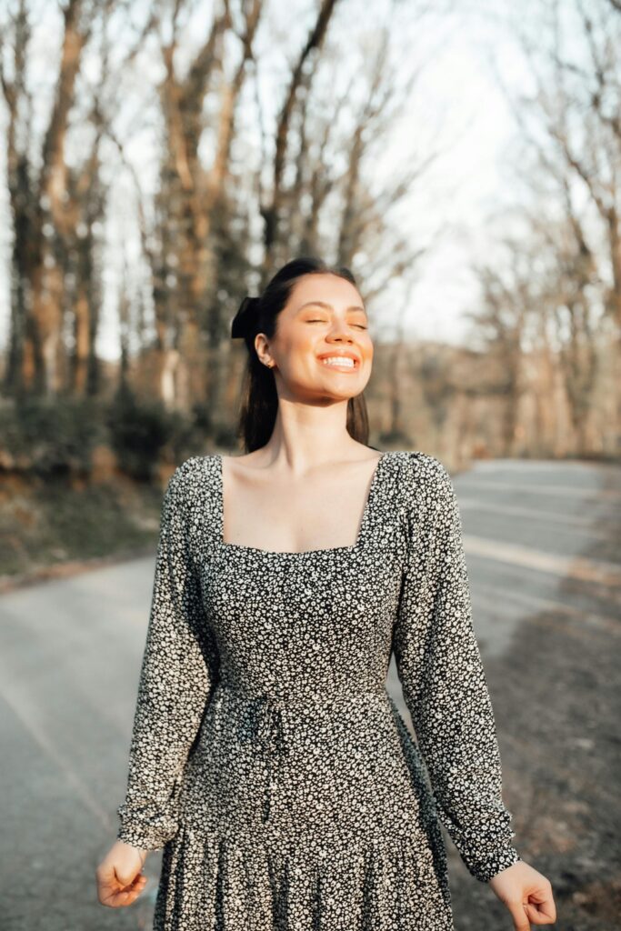 Woman with eyes closed, smiling on a sunny day in nature.